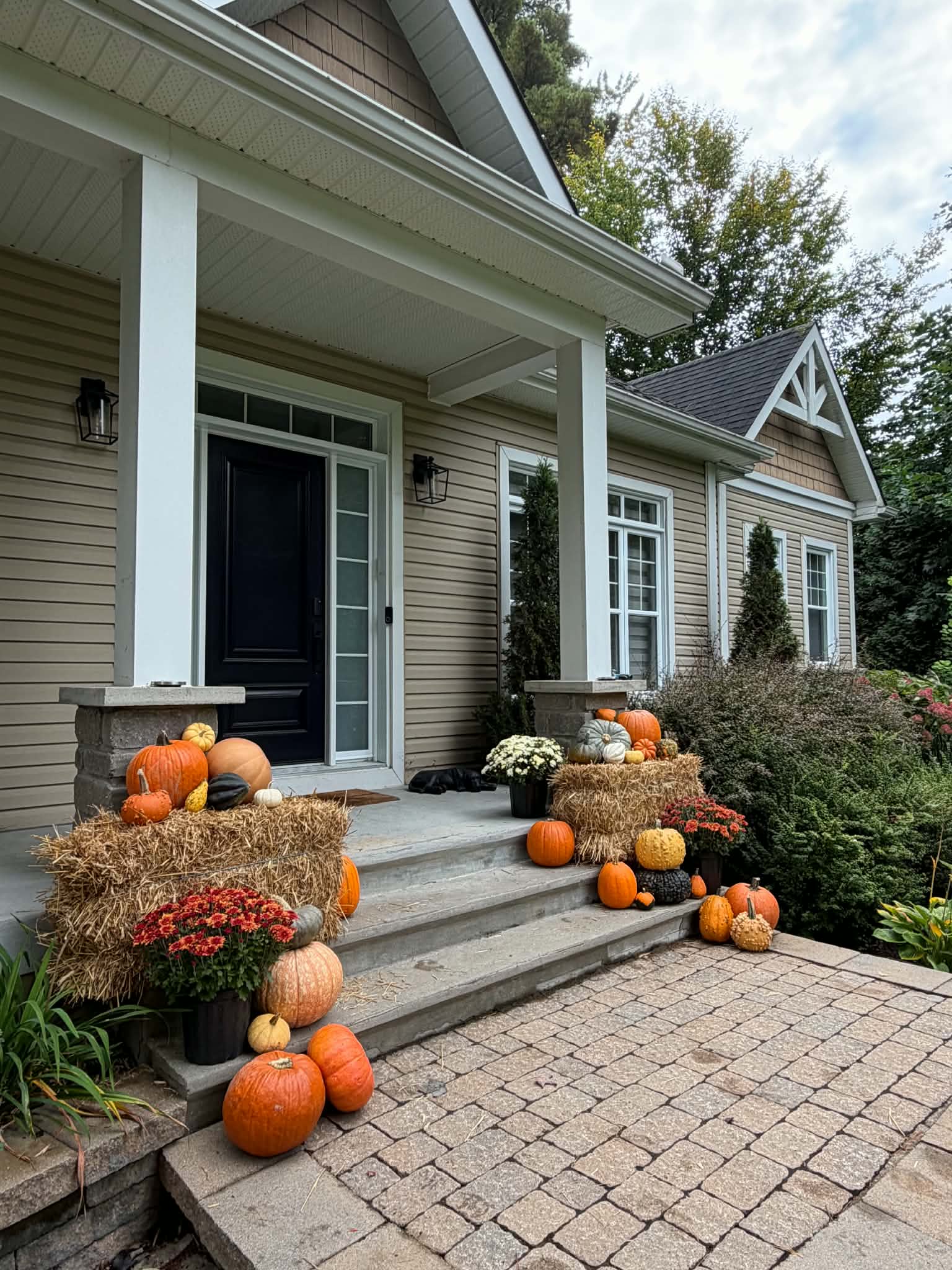 Lakeside veranda autumn entrance display with white ghost pumpkins and golden hay bales in Notre-Dame-de-l'Île-Perrot